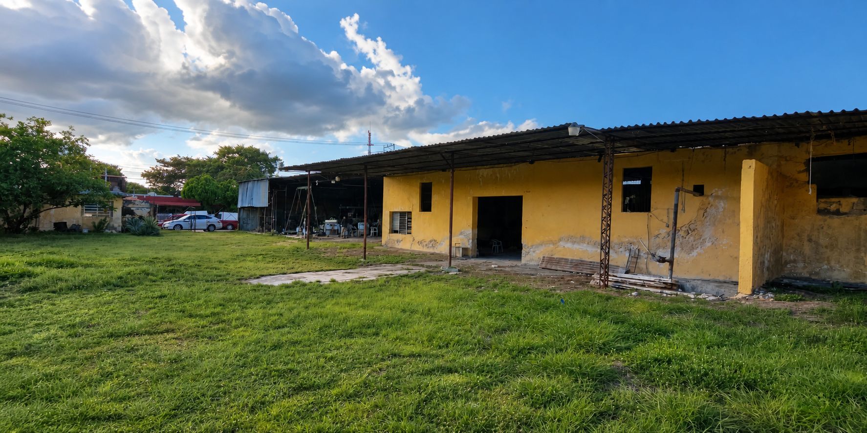 Vista actual del predio MACASA con área verde y construcciones existentes de color amarillo
